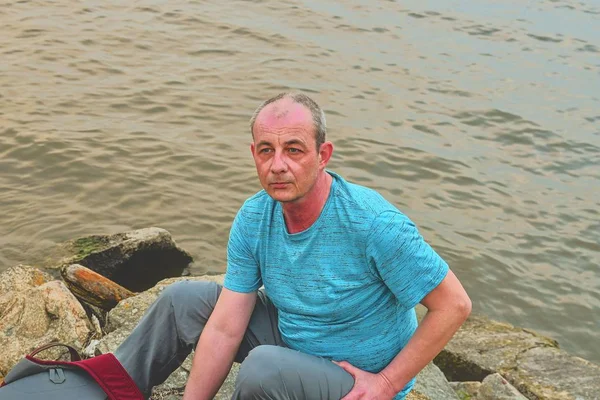 Homem de meia idade sentado na margem do lago. Solitude homem maduro sentado no banco. Conceito de solidão — Fotografia de Stock