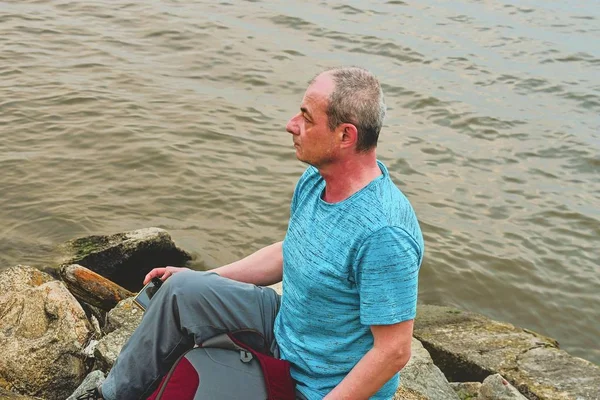 Belterület éves ember ül a tó partján. Magány érett ember ül a bank. Magány fogalmának — Stock Fotó