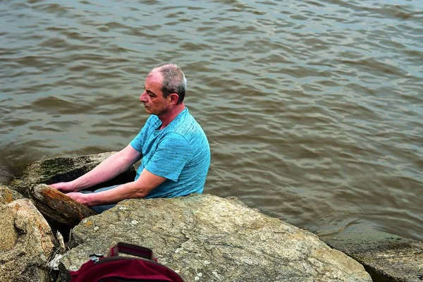 Belterület éves ember ül a tó partján. Magány érett ember ül a bank. Magány fogalmának — Stock Fotó