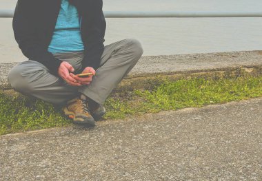 Orta göl kıyısında oturan adam yaşlı. Yalnızlık olgun adam cep telefonuyla ilgili banka. Activ adam kavramı