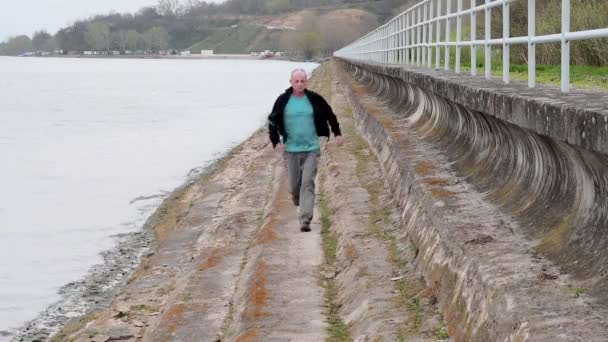 Uomo di mezza età che corre sulla riva del lago. Solitudine uomo maturo che corre sulla riva. Concetto di uomo attivo — Video Stock