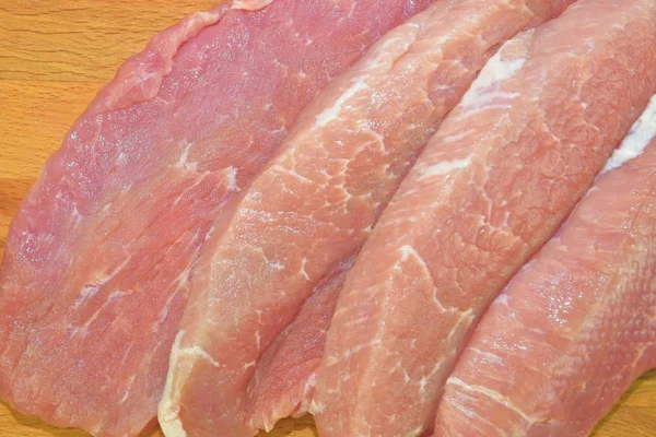 Raw pork loin chops on a cutting board on brown cutting board. Slices of pork steaks. Pork chops ready to fry. Selective focus — Stock Photo, Image