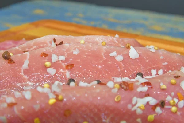 Raw pork loin chops on a cutting board with salt, pepper on brown cutting board. Slices of pork steaks. Pork chops ready to fry. Selective focus