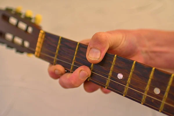 Ruka muže hrajícího na starou akustickou kytaru. Stará kytarová hlava s ladicími kolíky. — Stock fotografie