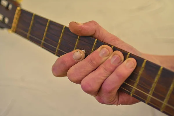 Mano dell'uomo che suona la vecchia chitarra acustica. Vecchia testa di chitarra con picchetti sintonizzazione . — Foto Stock