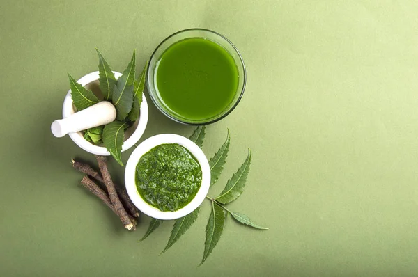 Yeşil zemin üzerine harç ve havaneli neem Yapıştır, suyu ve dallar ile tıbbi Neem yaprağı