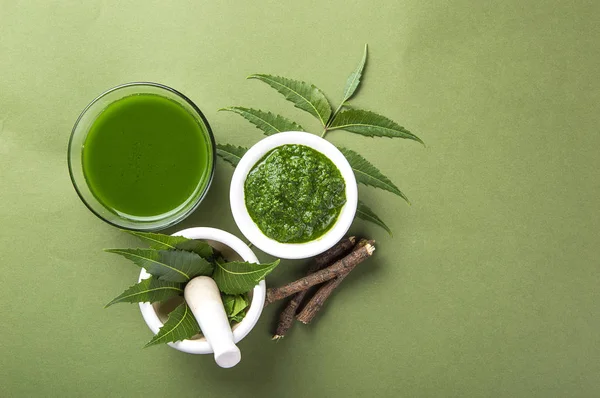 Yeşil zemin üzerine harç ve havaneli neem Yapıştır, suyu ve dallar ile tıbbi Neem yaprağı