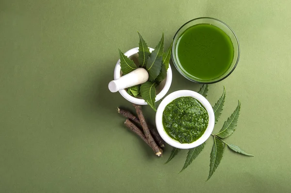 Yeşil zemin üzerine harç ve havaneli neem Yapıştır, suyu ve dallar ile tıbbi Neem yaprağı