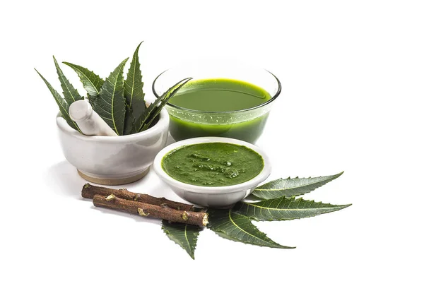 Medicinal Neem leaves in mortar and pestle with neem paste, juice and twigs on white background — Stock Photo, Image