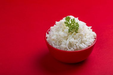 Kırmızı bir arka plan üzerinde kırmızı bir kasede düz beyaz basmati pirinç pişmiş