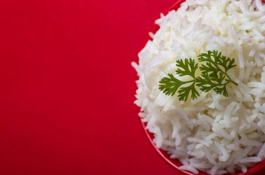 Kırmızı bir arka plan üzerinde kırmızı bir kasede düz beyaz basmati pirinç pişmiş