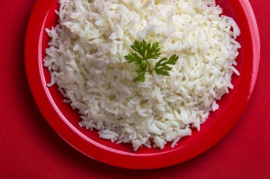 Düz beyaz basmati pirinç kırmızı zemin üzerine kırmızı bir tabak içinde pişmiş