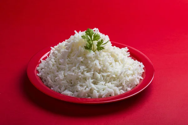 Cooked plain white basmati rice in a red plate on red background