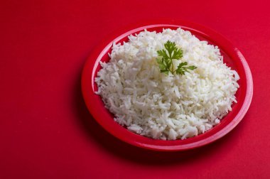 Düz beyaz basmati pirinç kırmızı zemin üzerine kırmızı bir tabak içinde pişmiş