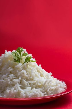 Düz beyaz basmati pirinç kırmızı zemin üzerine kırmızı bir tabak içinde pişmiş