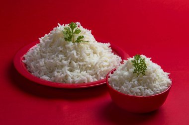 Düz beyaz basmati pirinç kase ve plaka kırmızı zemin üzerine pişmiş.