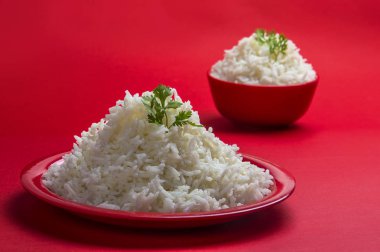 Düz beyaz basmati pirinç kase ve plaka kırmızı zemin üzerine pişmiş.