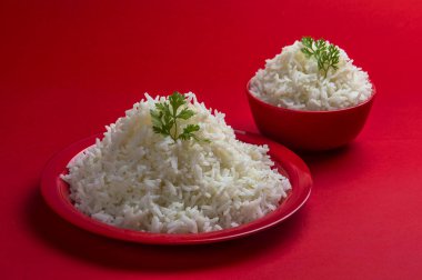 Düz beyaz basmati pirinç kase ve plaka kırmızı zemin üzerine pişmiş.