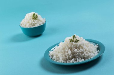 Düz beyaz basmati pirinç bir mavi plaka ve mavi arka plan üzerinde kase pişmiş