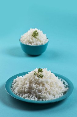 Düz beyaz basmati pirinç bir mavi plaka ve mavi arka plan üzerinde kase pişmiş