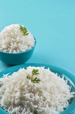 Düz beyaz basmati pirinç bir mavi plaka ve mavi arka plan üzerinde kase pişmiş