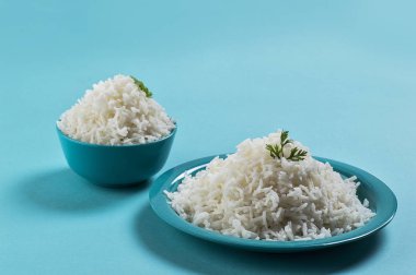 Düz beyaz basmati pirinç bir mavi plaka ve mavi arka plan üzerinde kase pişmiş
