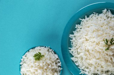 Düz beyaz basmati pirinç bir mavi plaka ve mavi arka plan üzerinde kase pişmiş