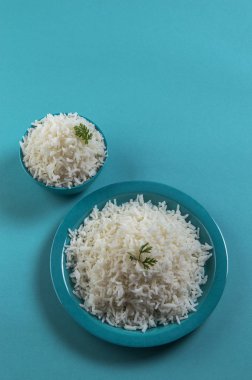Düz beyaz basmati pirinç bir mavi plaka ve mavi arka plan üzerinde kase pişmiş
