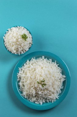 Düz beyaz basmati pirinç bir mavi plaka ve mavi arka plan üzerinde kase pişmiş