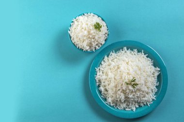 Düz beyaz basmati pirinç bir mavi plaka ve mavi arka plan üzerinde kase pişmiş