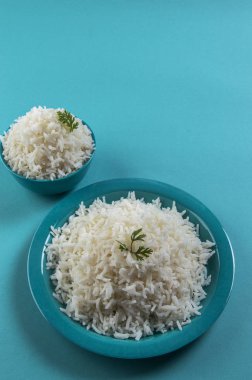 Düz beyaz basmati pirinç bir mavi plaka ve mavi arka plan üzerinde kase pişmiş