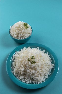Düz beyaz basmati pirinç bir mavi plaka ve mavi arka plan üzerinde kase pişmiş