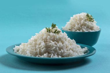 Düz beyaz basmati pirinç bir mavi plaka ve mavi arka plan üzerinde kase pişmiş