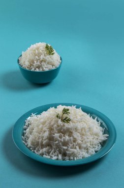 Düz beyaz basmati pirinç bir mavi plaka ve mavi arka plan üzerinde kase pişmiş