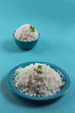 Düz beyaz basmati pirinç bir mavi plaka ve mavi arka plan üzerinde kase pişmiş