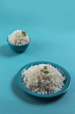 Düz beyaz basmati pirinç bir mavi plaka ve mavi arka plan üzerinde kase pişmiş