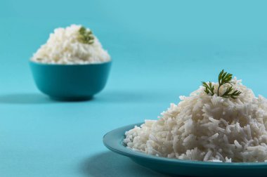 Düz beyaz basmati pirinç bir mavi plaka ve mavi arka plan üzerinde kase pişmiş