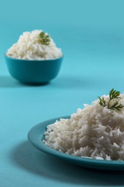 Düz beyaz basmati pirinç bir mavi plaka ve mavi arka plan üzerinde kase pişmiş