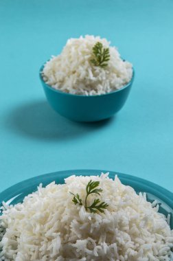 Düz beyaz basmati pirinç bir mavi plaka ve mavi arka plan üzerinde kase pişmiş