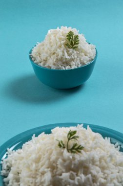 Düz beyaz basmati pirinç bir mavi plaka ve mavi arka plan üzerinde kase pişmiş