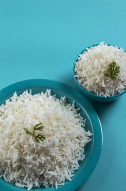 Düz beyaz basmati pirinç bir mavi plaka ve mavi arka plan üzerinde kase pişmiş