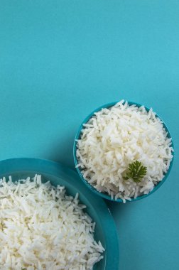 Düz beyaz basmati pirinç bir mavi plaka ve mavi arka plan üzerinde kase pişmiş