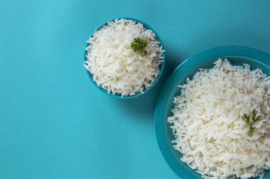 Düz beyaz basmati pirinç bir mavi plaka ve mavi arka plan üzerinde kase pişmiş