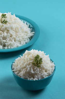 Düz beyaz basmati pirinç bir mavi plaka ve mavi arka plan üzerinde kase pişmiş