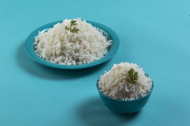 Düz beyaz basmati pirinç bir mavi plaka ve mavi arka plan üzerinde kase pişmiş