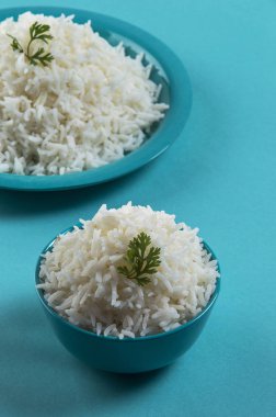 Düz beyaz basmati pirinç bir mavi plaka ve mavi arka plan üzerinde kase pişmiş