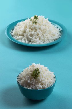 Düz beyaz basmati pirinç bir mavi plaka ve mavi arka plan üzerinde kase pişmiş