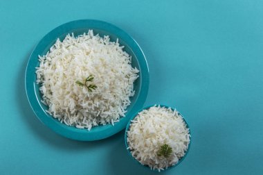 Düz beyaz basmati pirinç bir mavi plaka ve mavi arka plan üzerinde kase pişmiş