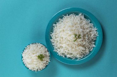 Düz beyaz basmati pirinç bir mavi plaka ve mavi arka plan üzerinde kase pişmiş