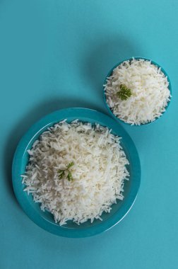Düz beyaz basmati pirinç bir mavi plaka ve mavi arka plan üzerinde kase pişmiş